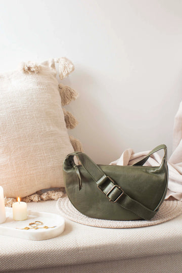 Green leather bag on a textured surface with a soft white background