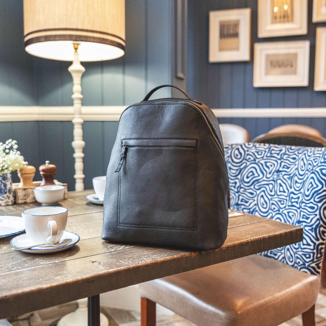 Black leather backpack on rustic wooden table in country-themed hotel setting, blending sophistication with rugged charm.