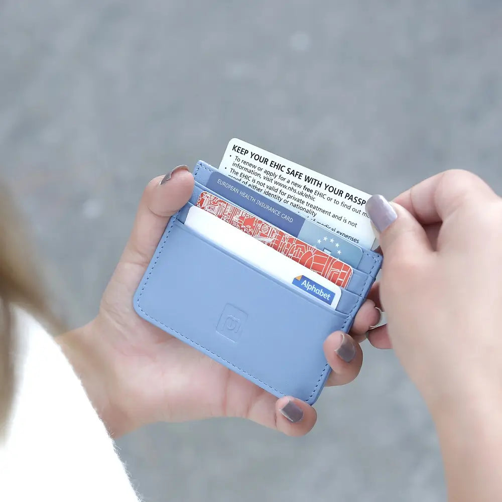 A person holding a pastel blue leather card holder.