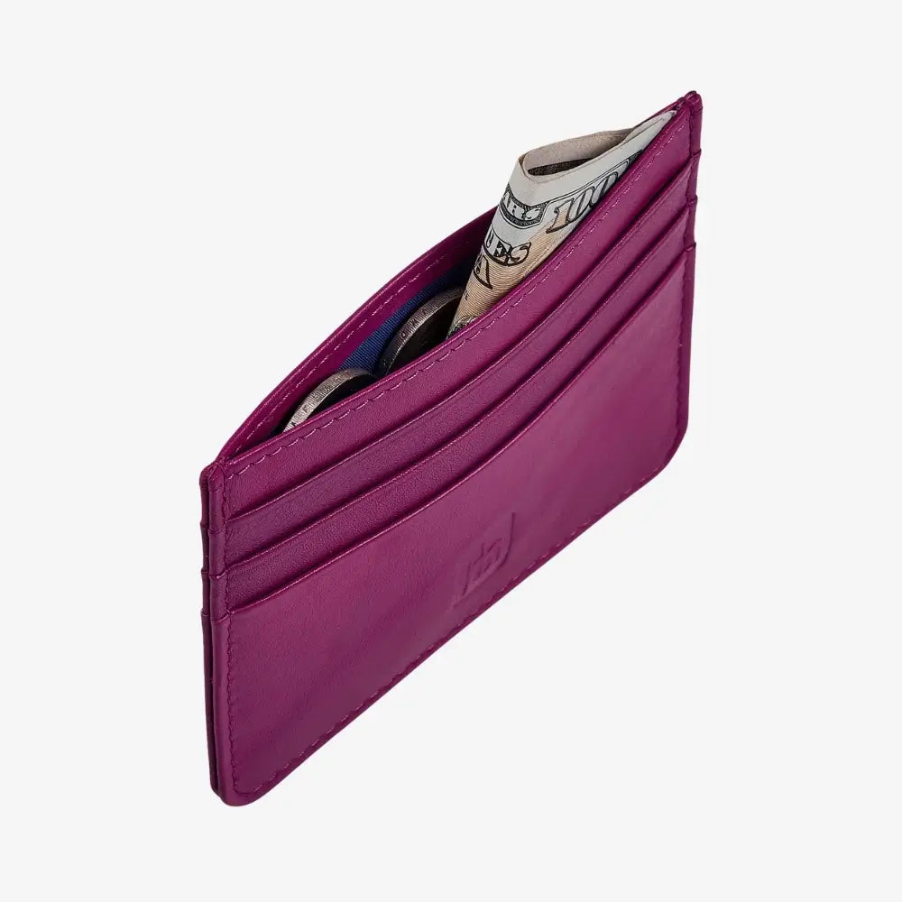 A Fuchsia leather card holder wallet shown open, containing several cards and a rolled dollar bill, on a light gray background.