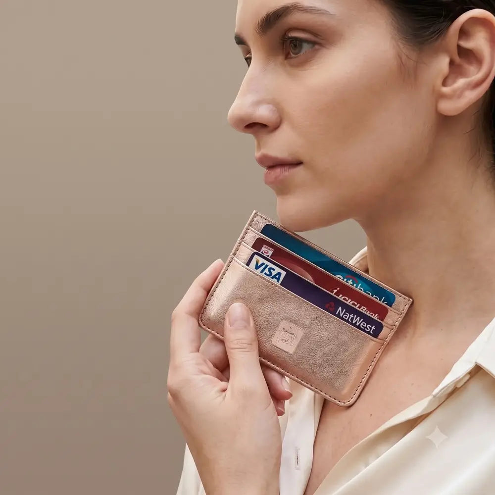 A person holding rose gold leather card holder .
