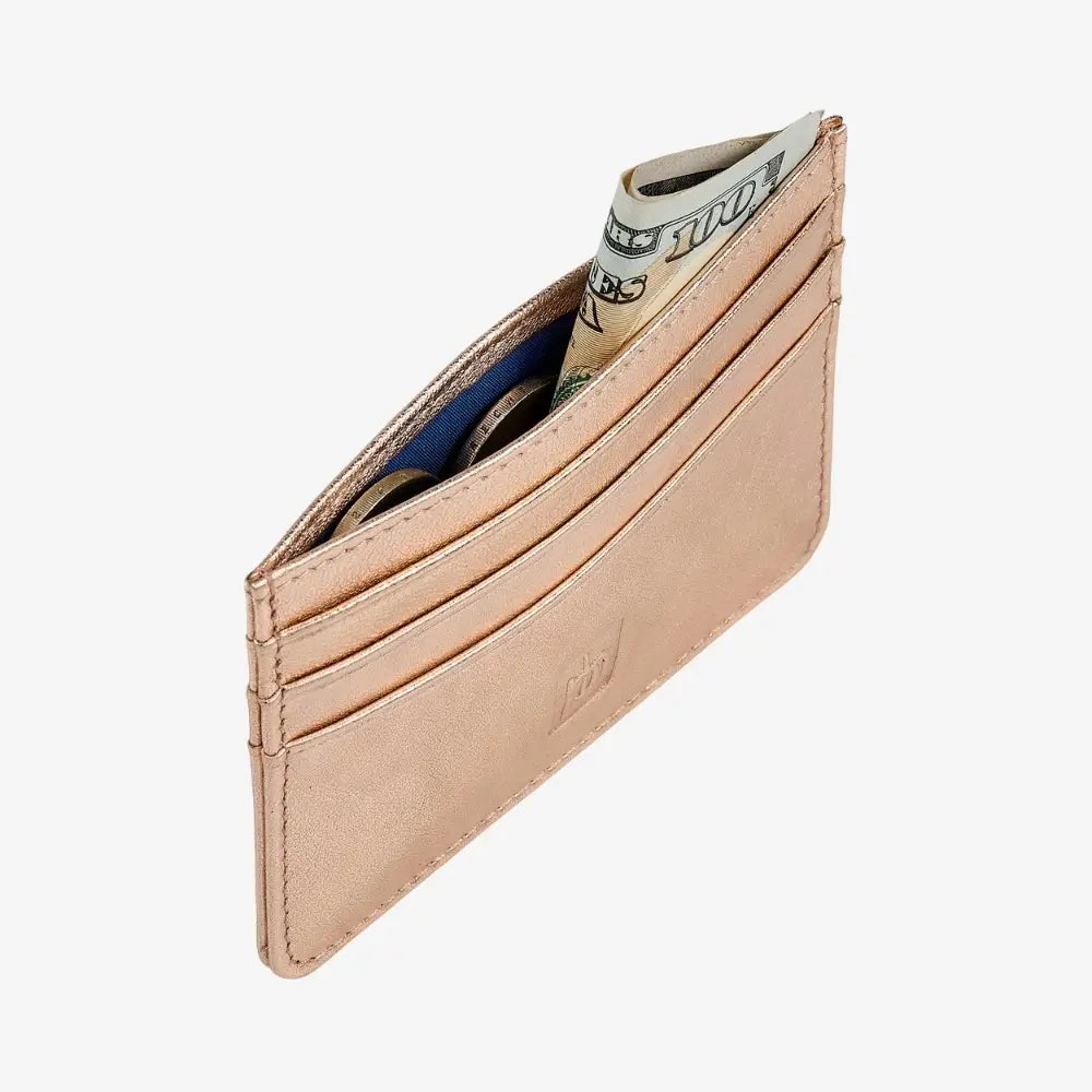 A slim, minimalist cardholder wallet in a rose gold leather finish, shown open with several credit cards and a dollar bill inserted. 