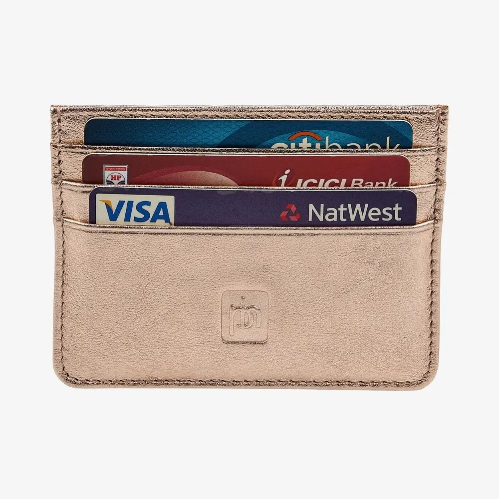 A slim, minimalist cardholder wallet in rosegold leather, shown with four credit cards inserted. The wallet features a debossed logo on the front and is photographed against a clean, light gray background.