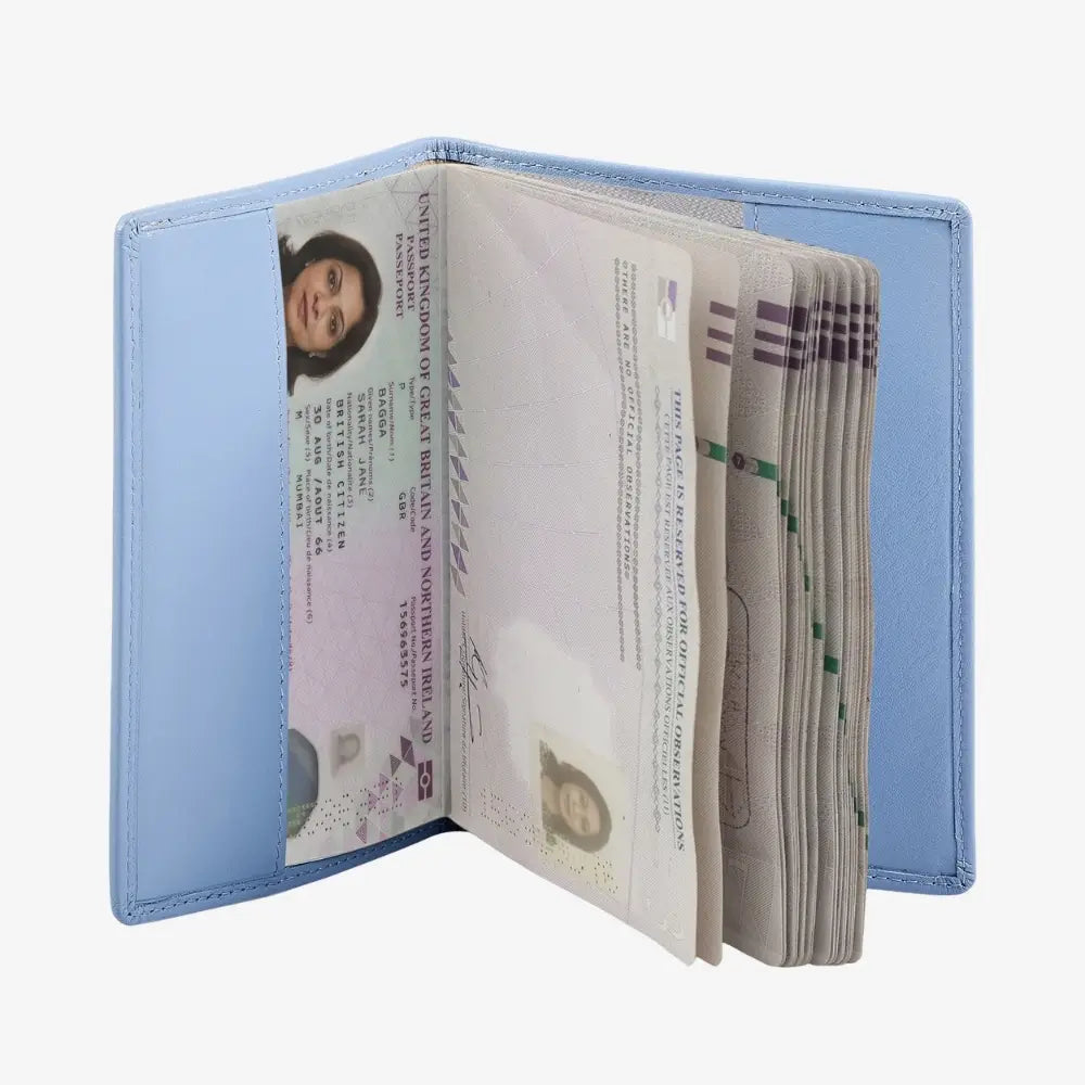 A light blue leather passport holder shown open, containing several passports and ID documents, photographed on a plain light gray background.