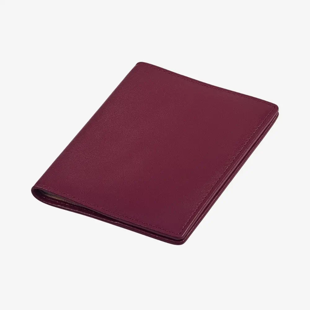 A burgundy leather passport holder with a textured finish, shown closed at an angle on a plain white background.