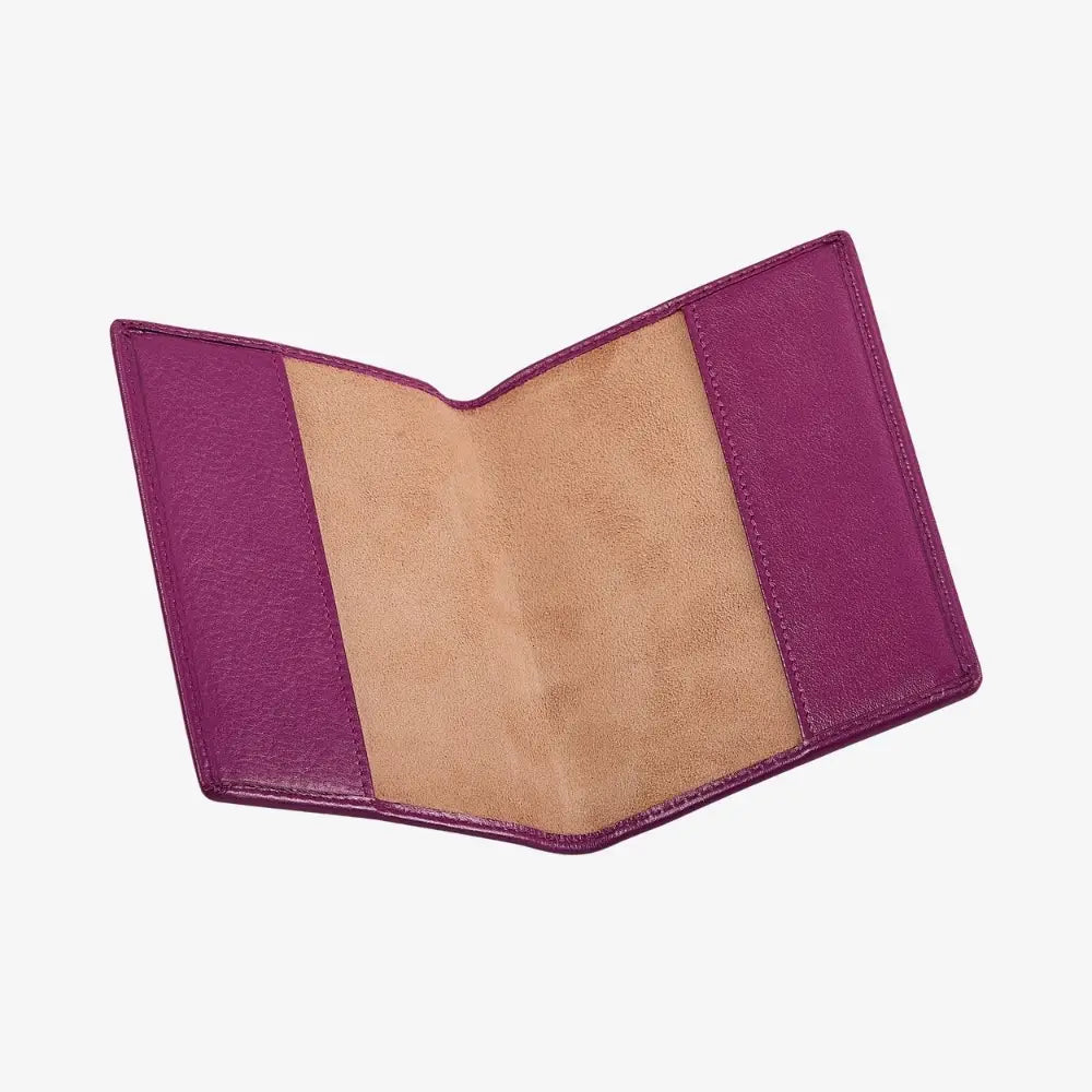 A fuchsia leather passport cover shown open, displaying a textured purple exterior and a tan suede interior, set against a plain white background.
