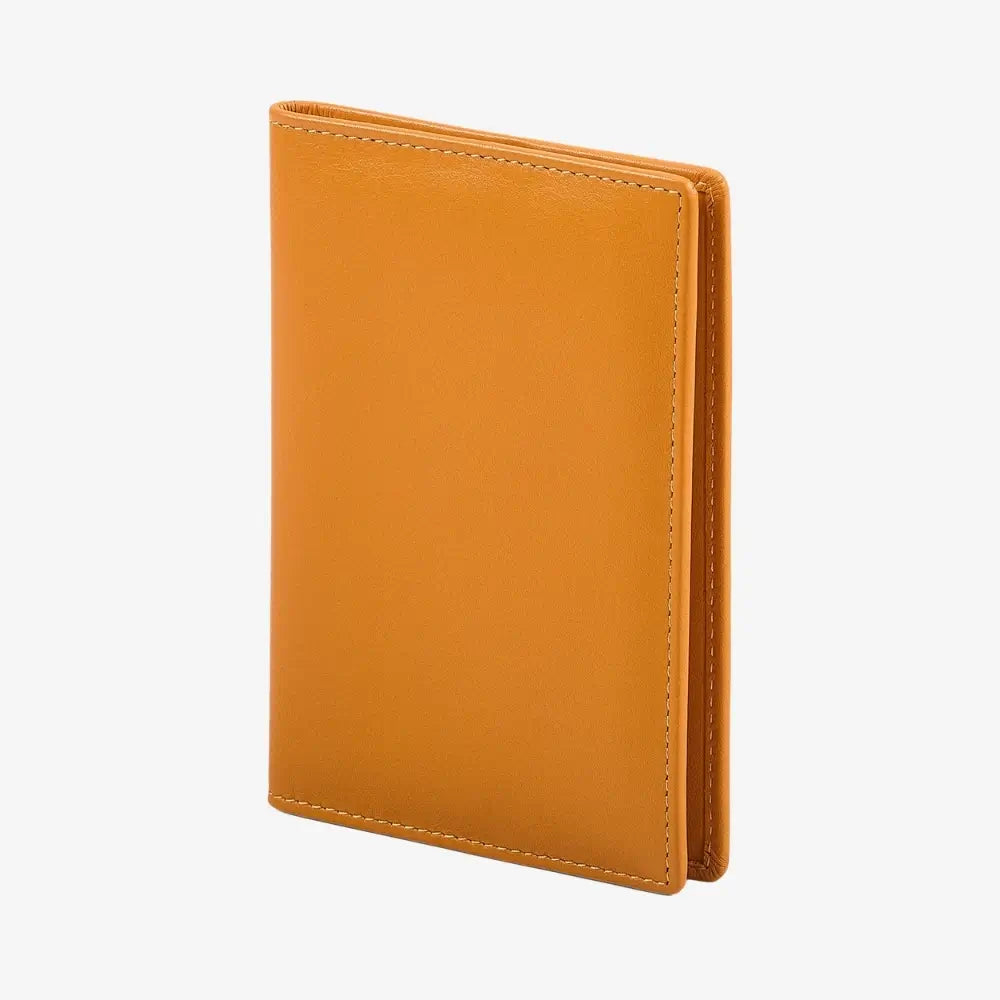 A slim, minimalist leather passport cover in a warm camel yellow color, shown standing upright at a slight angle against a clean, light gray background.