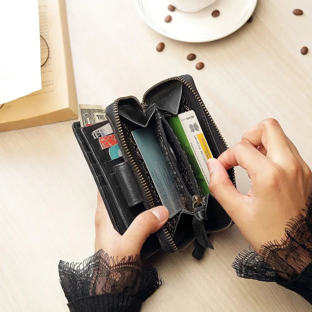 Person opening a black wallet on a light wooden surface with coffee beans and a cup in the background.