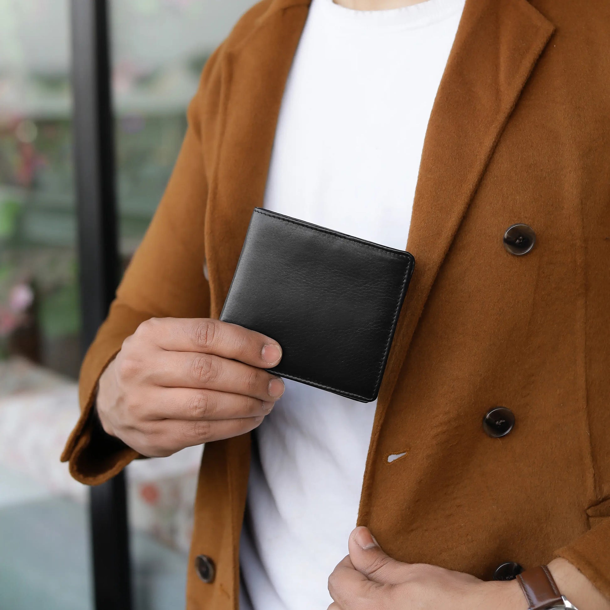 Person holding a black leather wallet with a blurred background