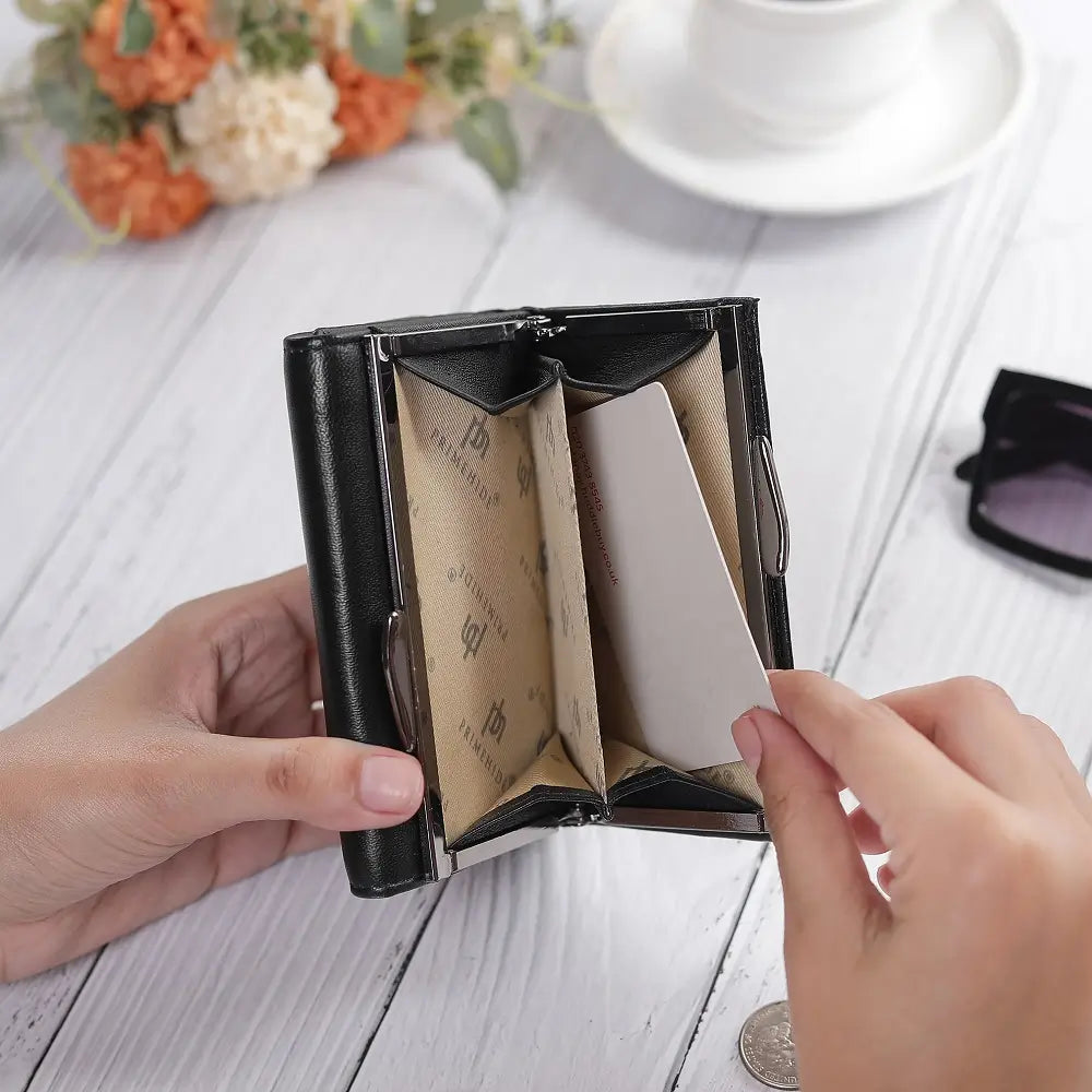 Person holding a black cardholder with business cards on a white wooden surface.