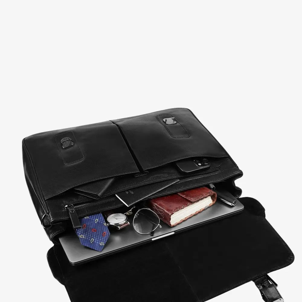 Black leather laptop bag with items like a watch, glasses, and a book inside on a white background