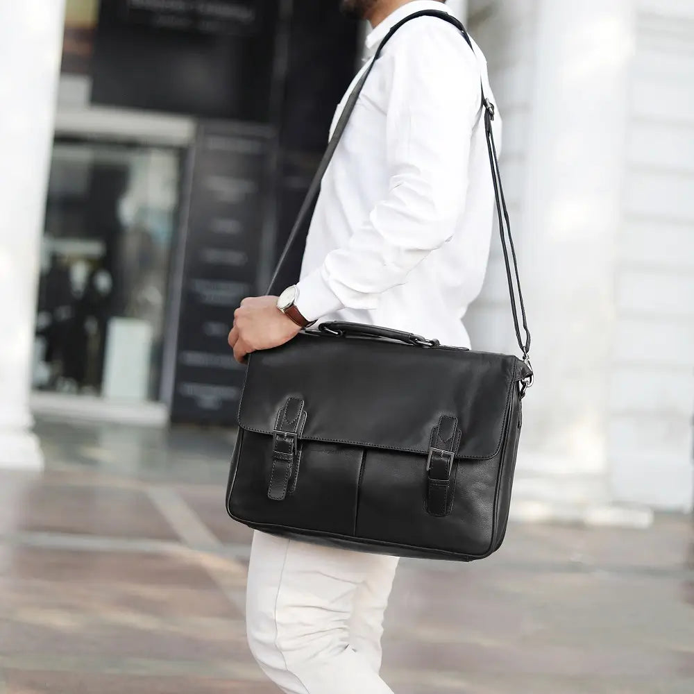 Person carrying a black leather laptop bag in an urban setting