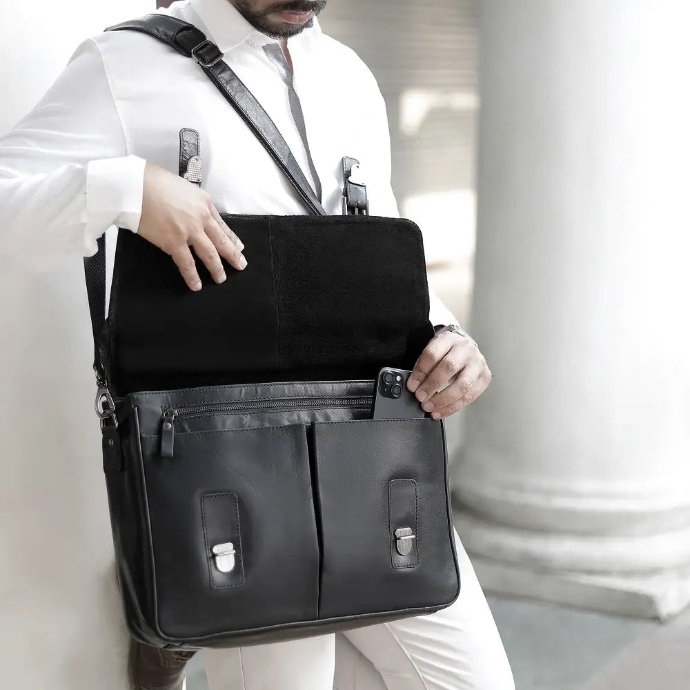 Man holding a black leather laptop bag in an indoor setting