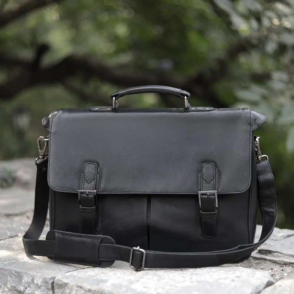 Black leather laptop bag on a stone surface with a blurred natural background