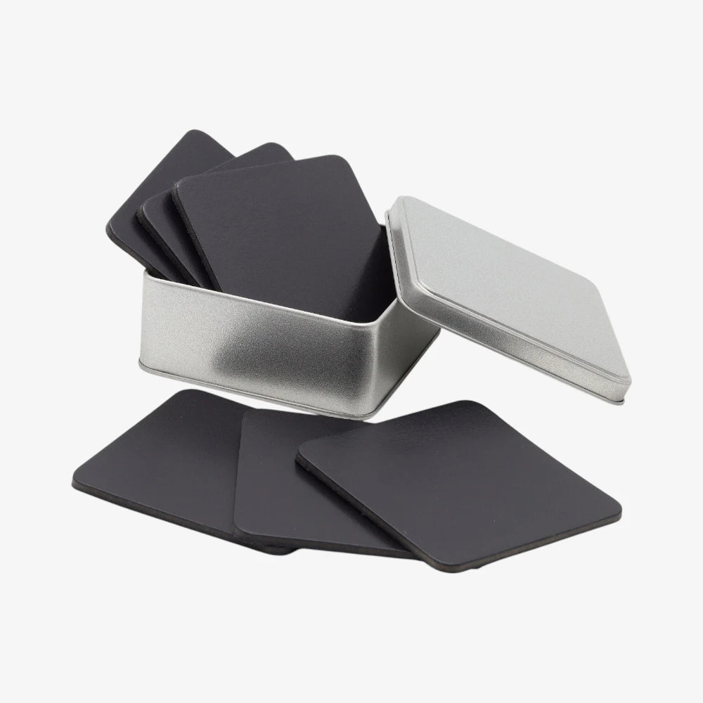 Set of black square coasters with a silver storage box on a white background