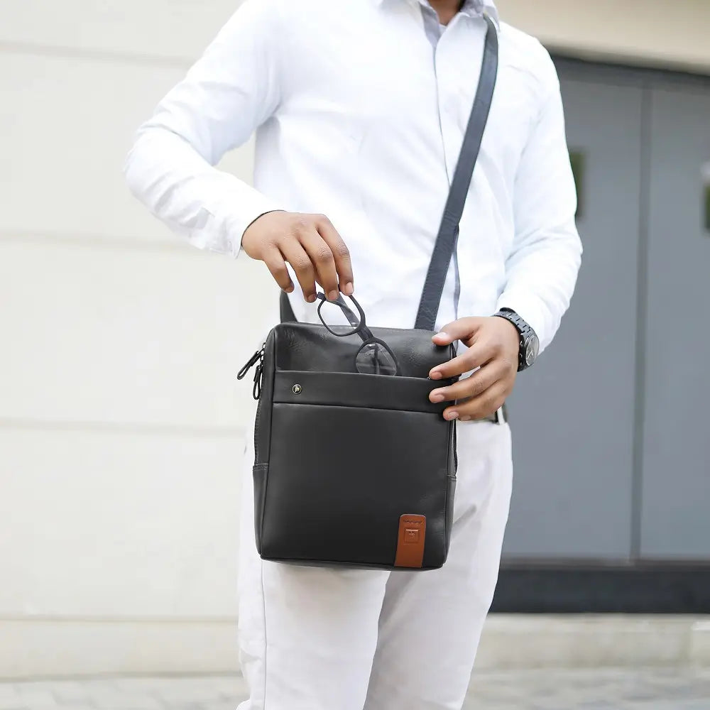 Person holding a black messenger 
 leather bag with a blurred background