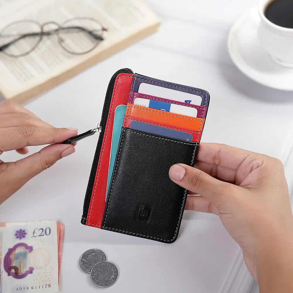 Black Card Holder purse with colorful card slots held by a hand on a table with a cup of coffee and glasses.