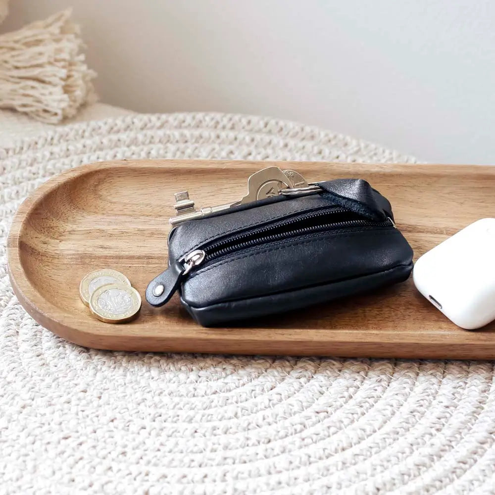 Life style view of Black Small Leather Zipper Keyring Pouch on grey background