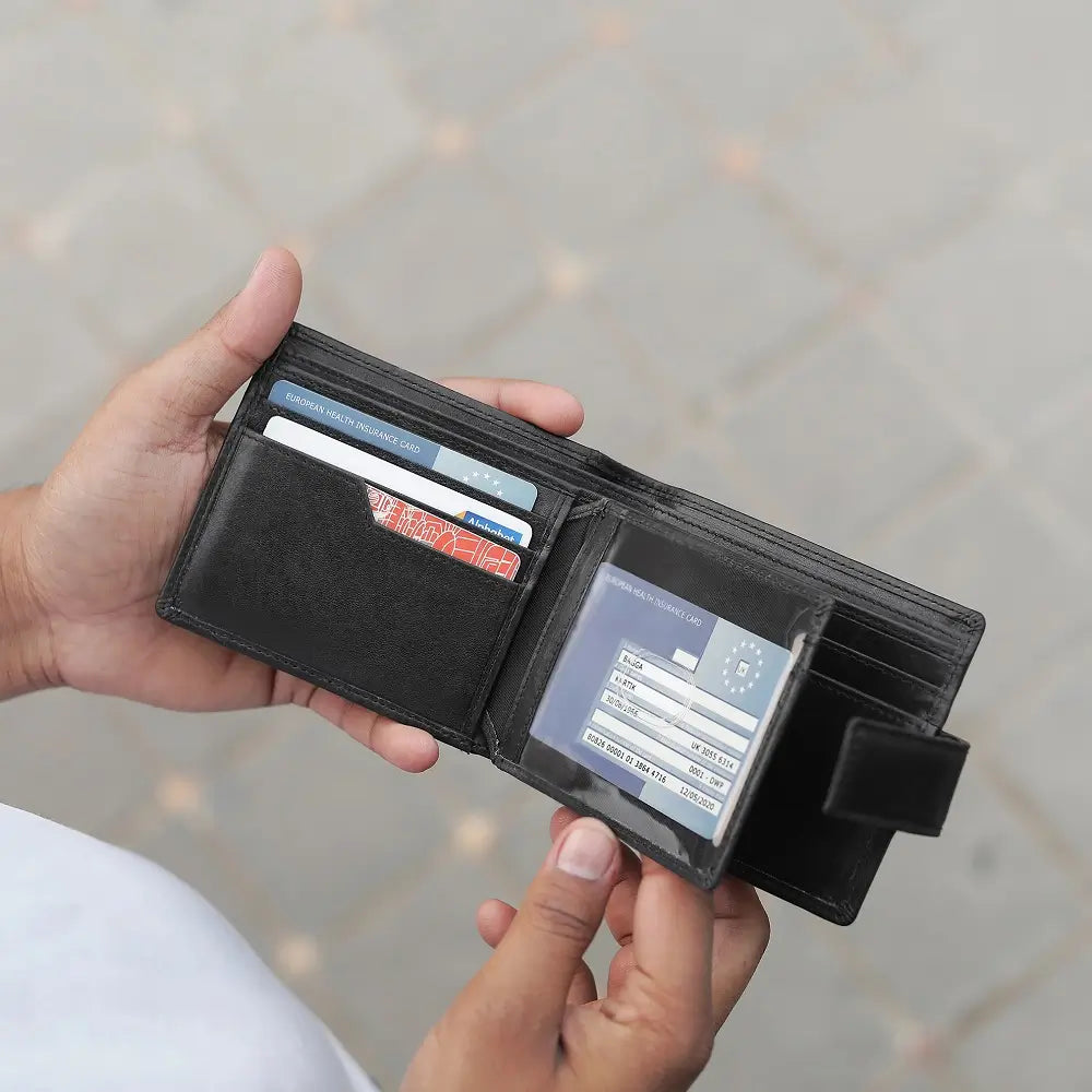 Person holding a black wallet with cards and a cardholder against a neutral background