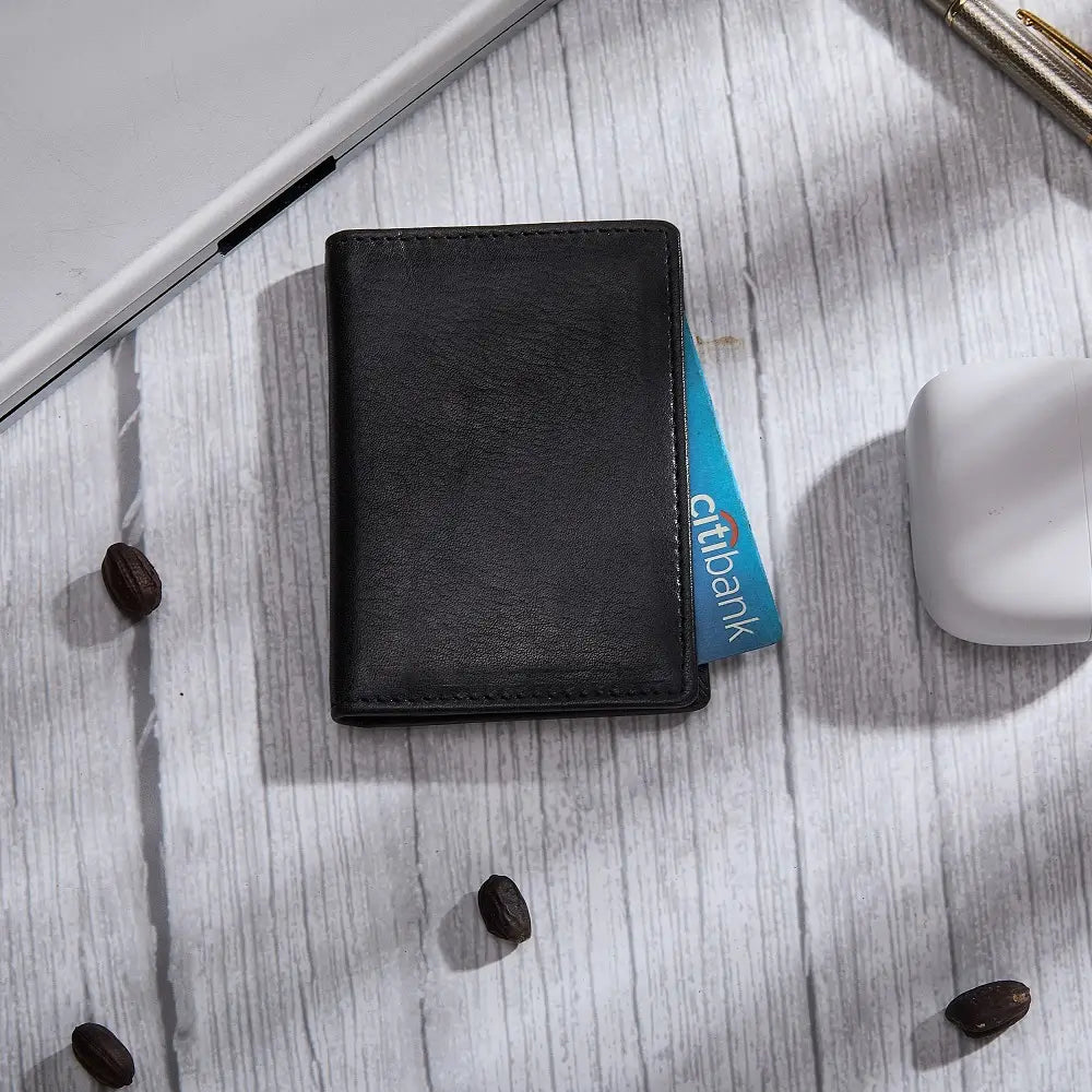 Black card holder on a light wooden surface with coffee beans.