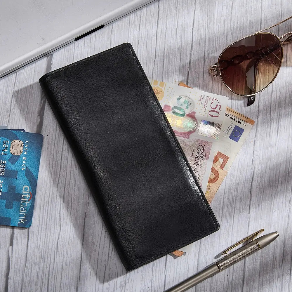 Black wallet with banknotes, sunglasses, and a pen on a wooden surface