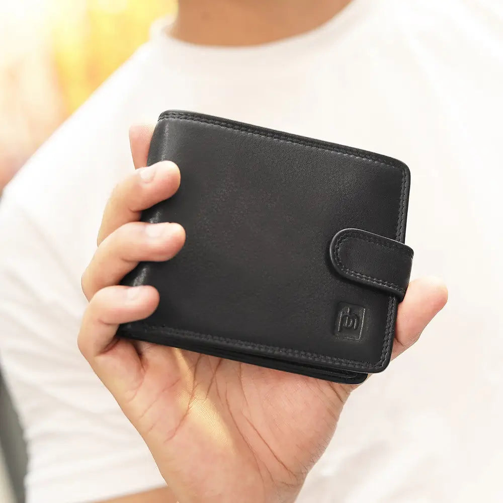 Person holding a black leather wallet with a visible brand logo.