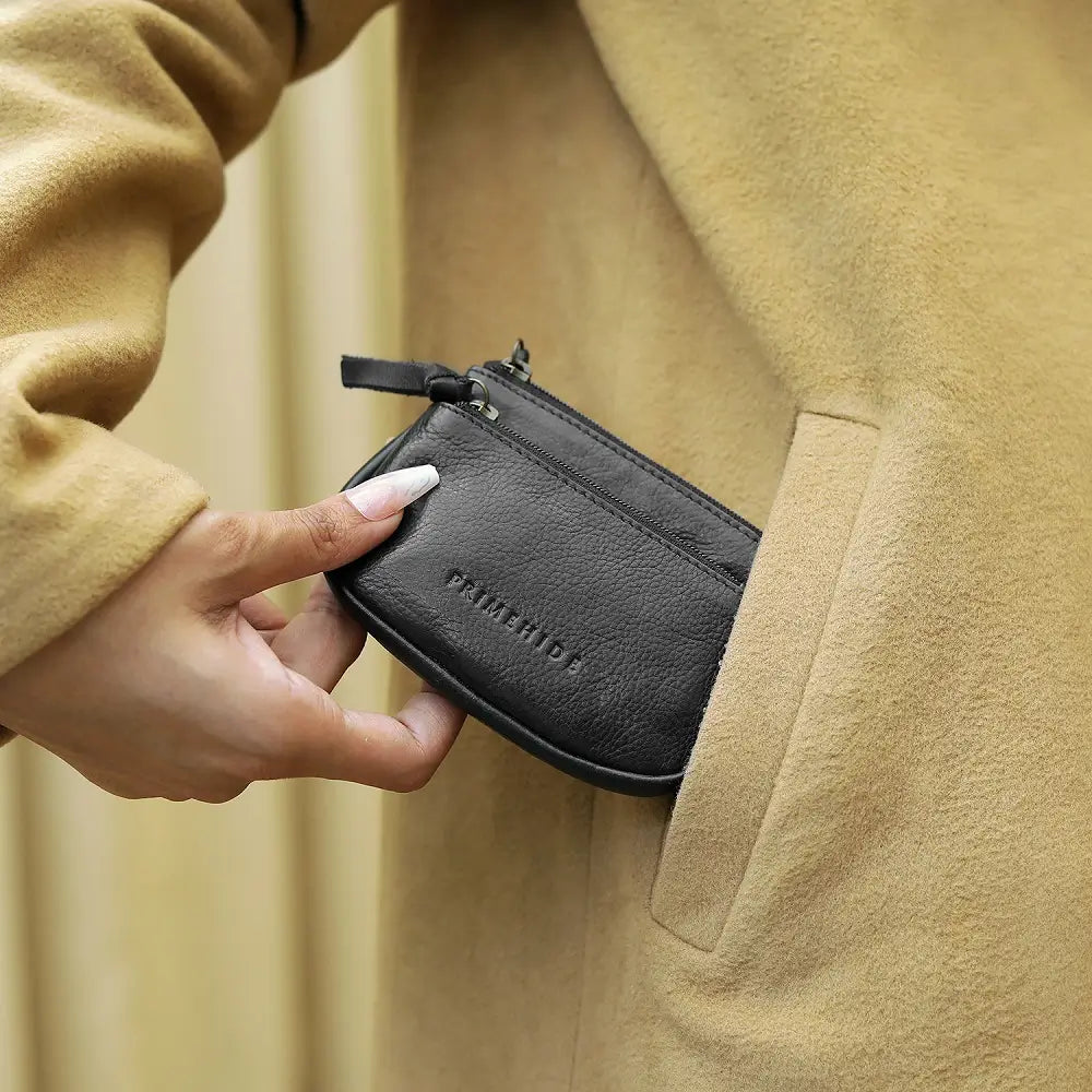 Person holding a black wallet with a beige coat