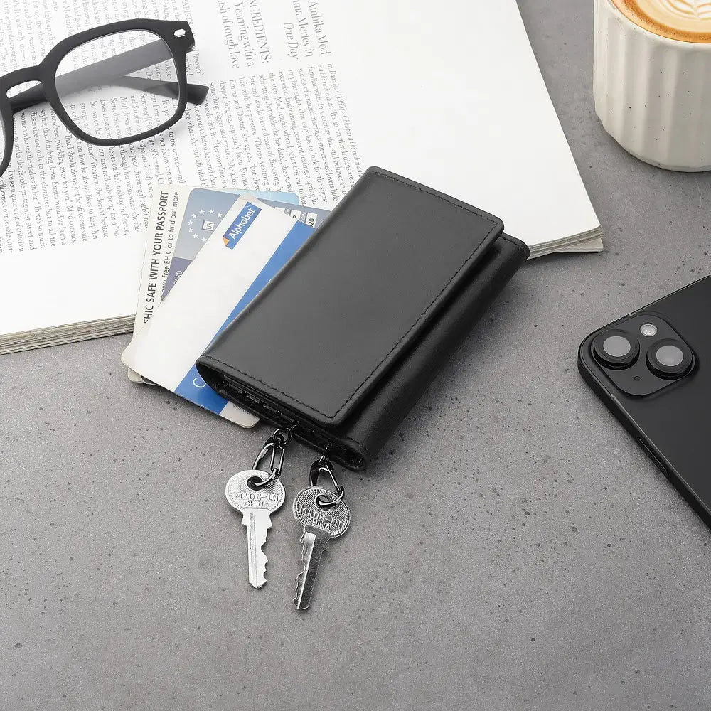 Black leather key holder wallet placed beside a glasses, coffee cup,cards and phone