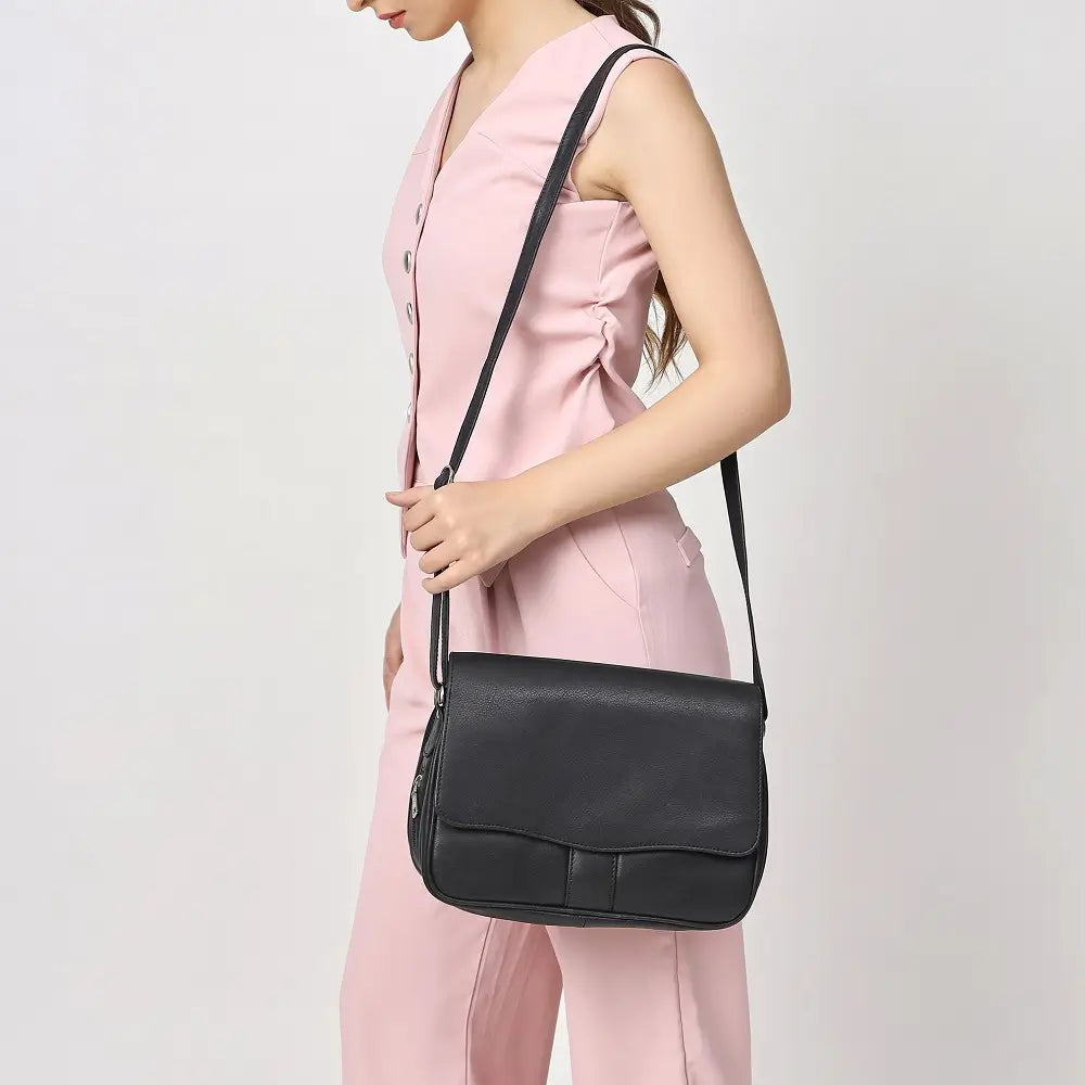 Person wearing a black shoulder bag against a plain background