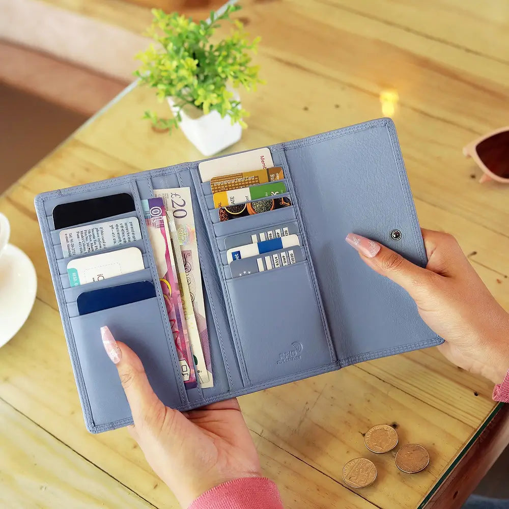 Blue wallet on a marble surface with coins and reading material