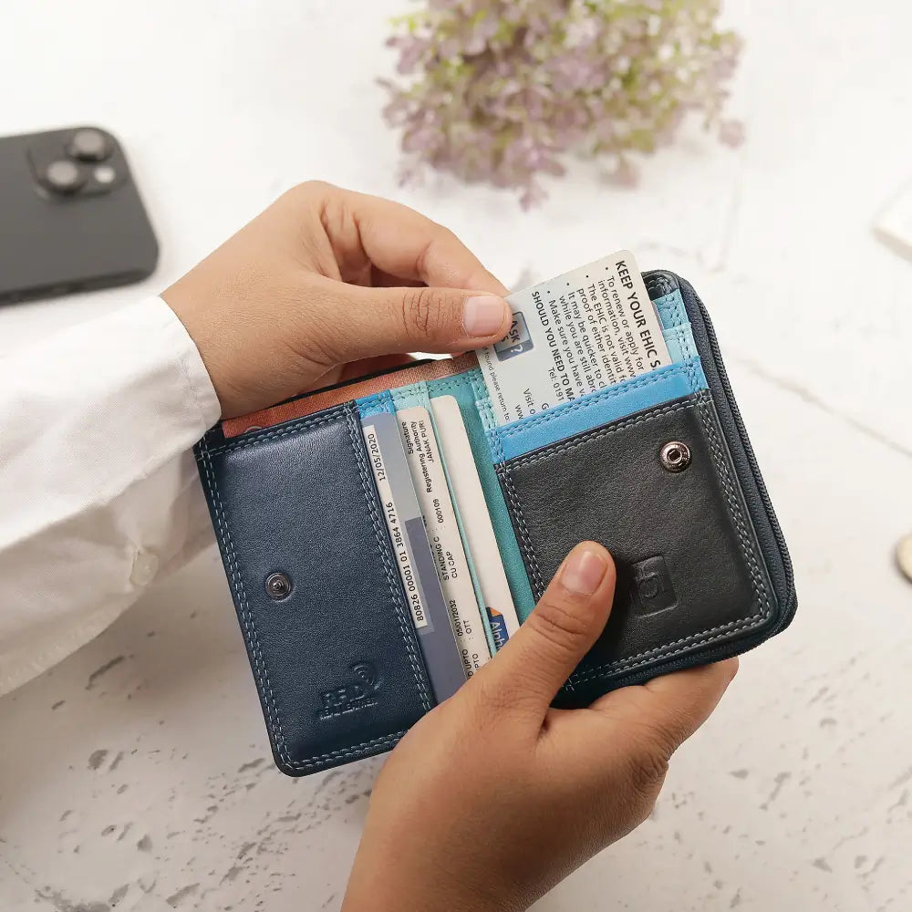 A person holds an open slim bifold wallet with multiple card slots and a cash pocket. 