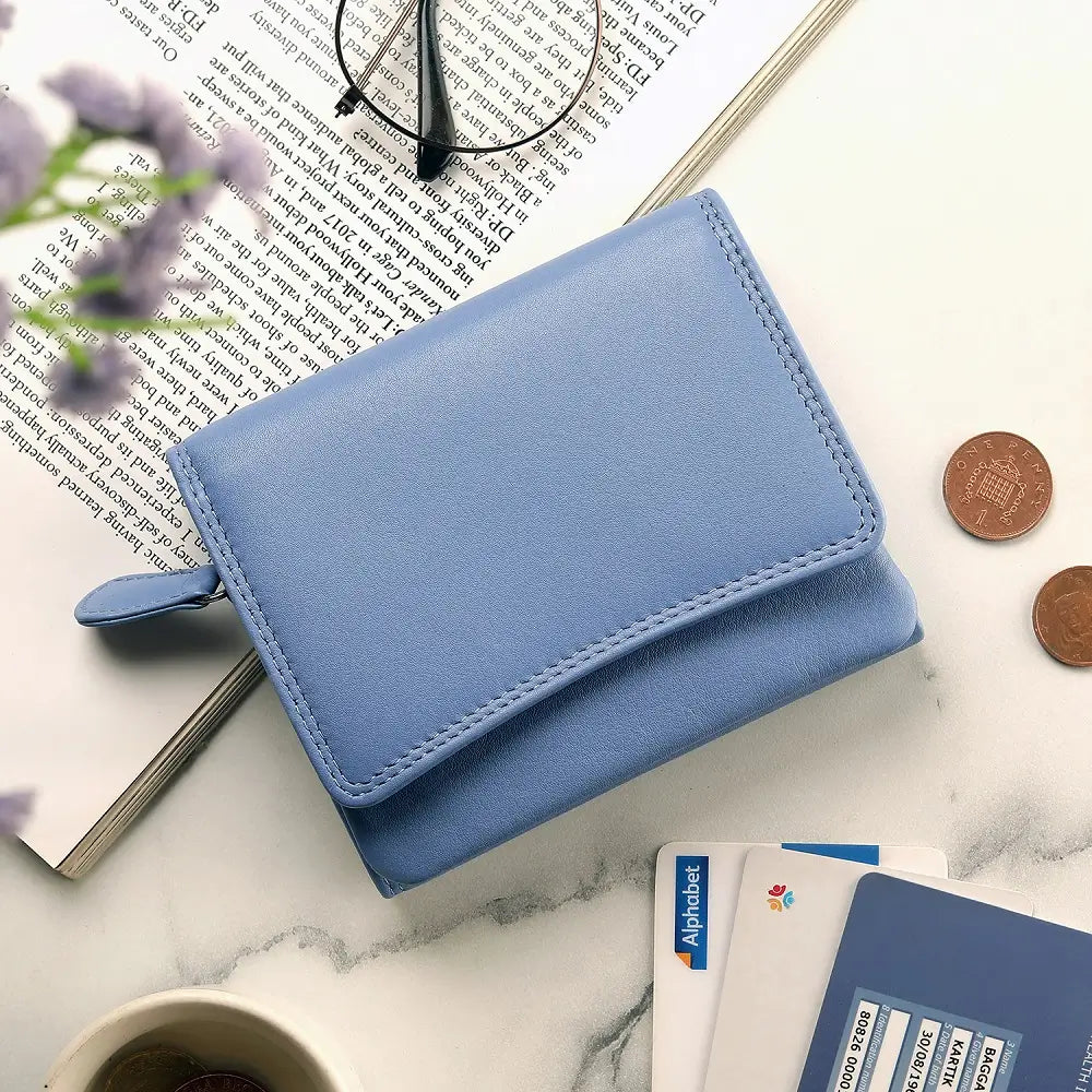 Blue wallet on a marble surface with books, coins, and a cup.