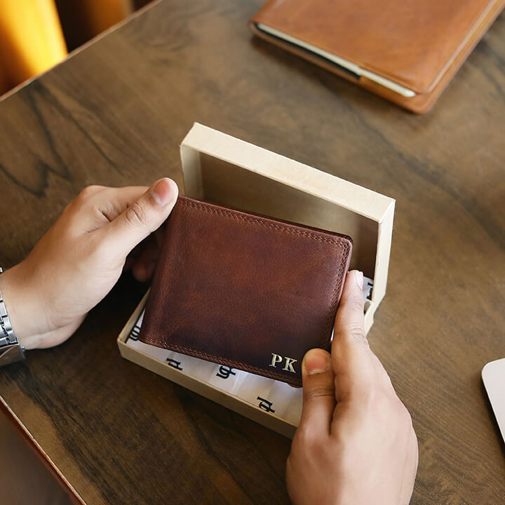 Brown leather wallet being held by a person with personalised initials 