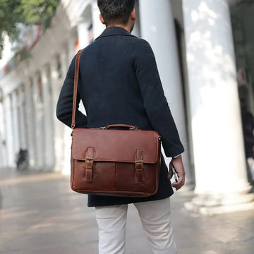 Person wearing a brown leather laptop bag  in an urban setting
