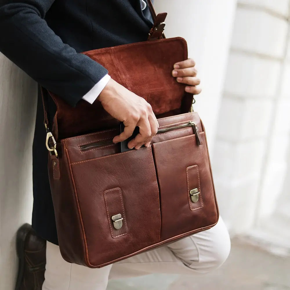 Person holding a brown leather laptop bag  indoors
