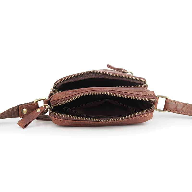 Brown leather crossbody bag with multiple zippers on a white background