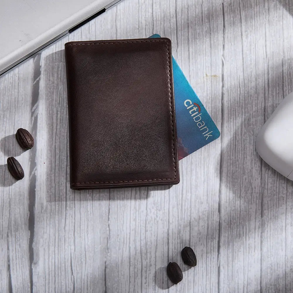 Brown leather card holder with a Citi card on a light wooden surface