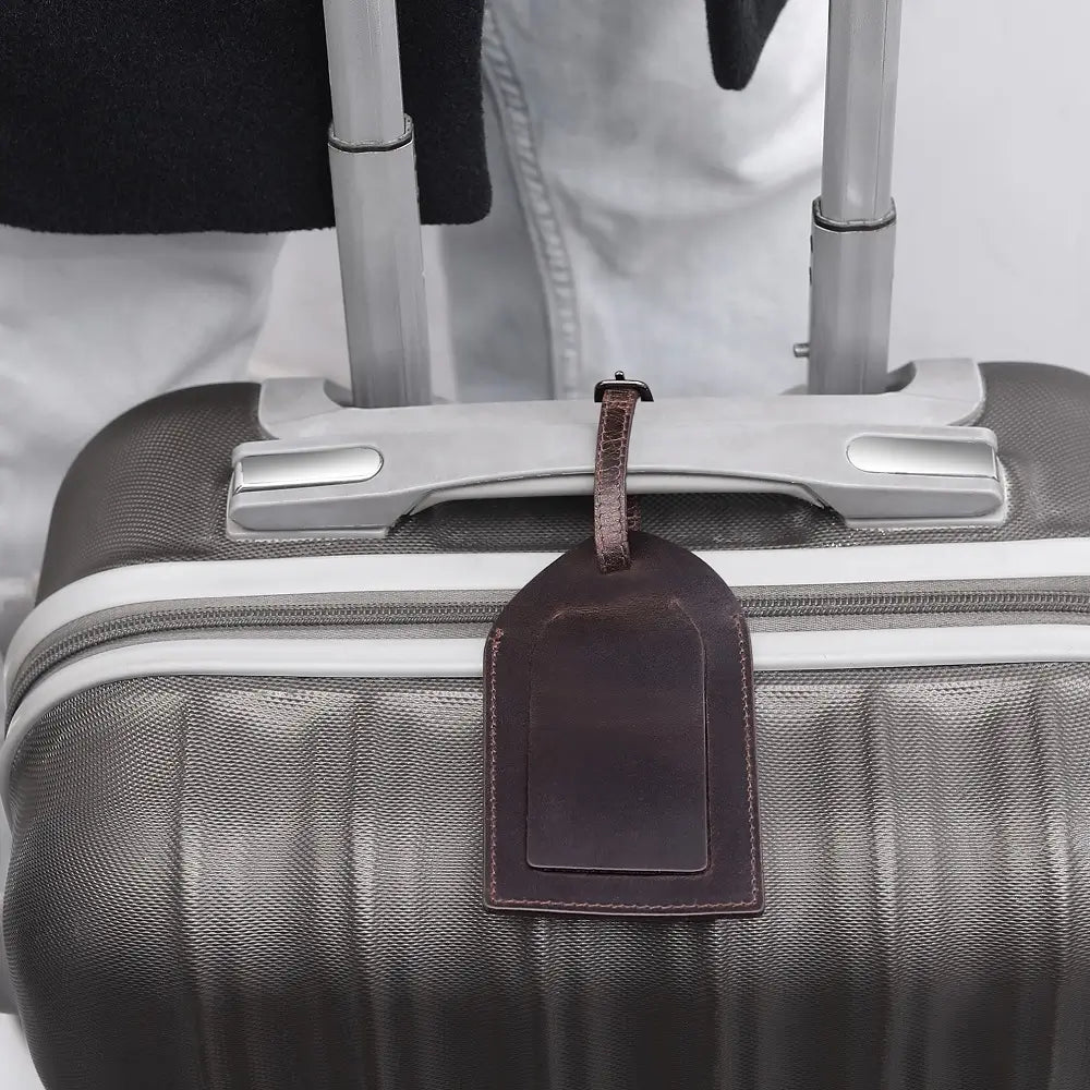 Brown leather luggage tag attached to a travel suitcase, adding classic elegance to travel gear.