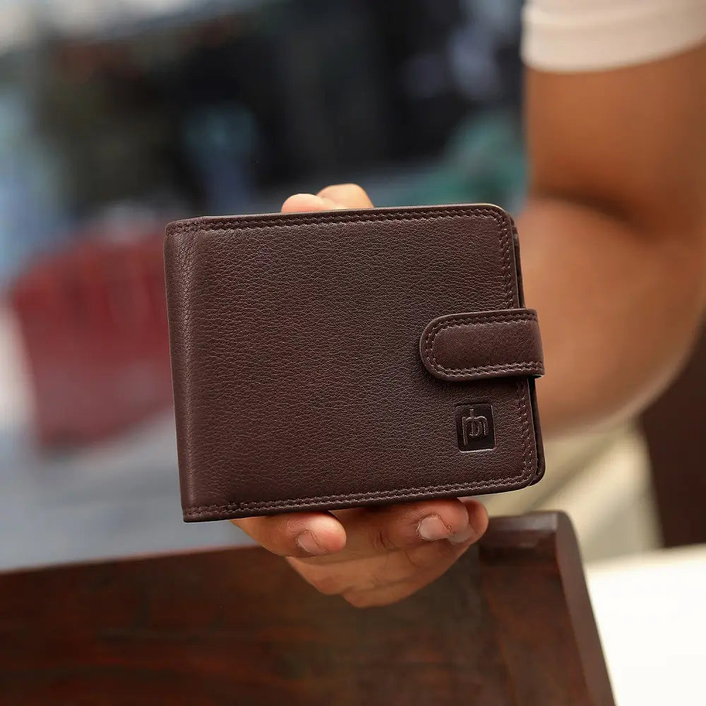 Brown leather wallet held by a person with a blurred background