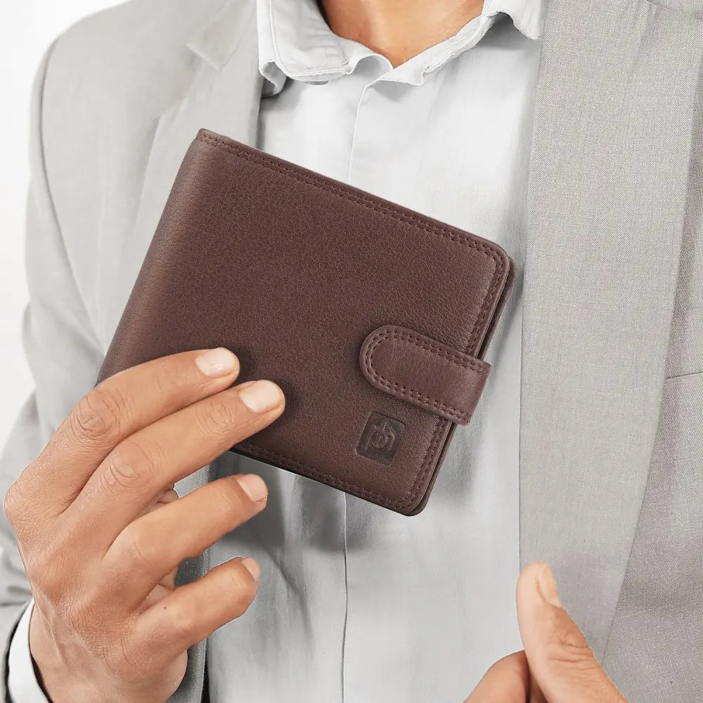 Person holding a brown leather wallet with a visible brand logo.