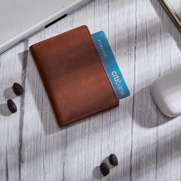 Chestnut leather card holder with a Citibank card on a light wooden surface