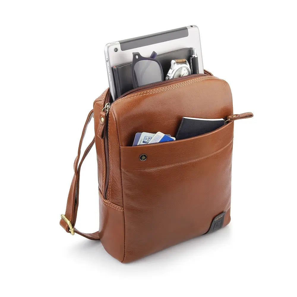 Tan leather messenger bag with items inside on a white background