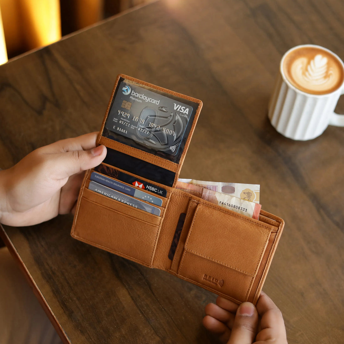 Person holding a cognac leather wallet with a blurred background