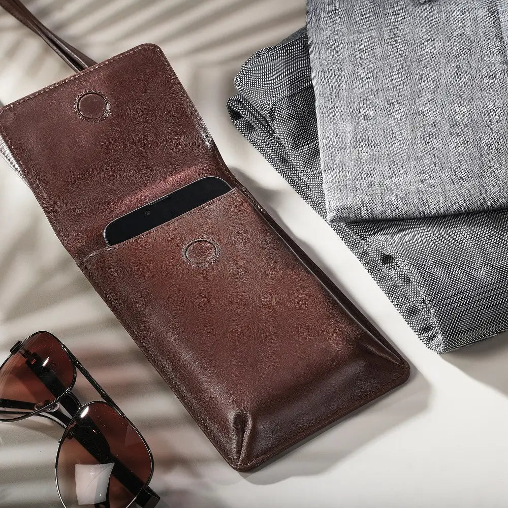 Cognac leather wallet with sunglasses and gray fabric on a light surface