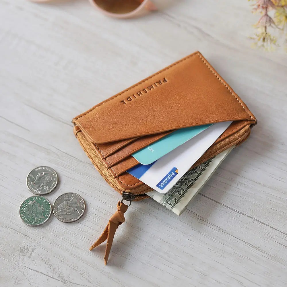 Cognac leather wallet with coins and cards on a light wooden surface