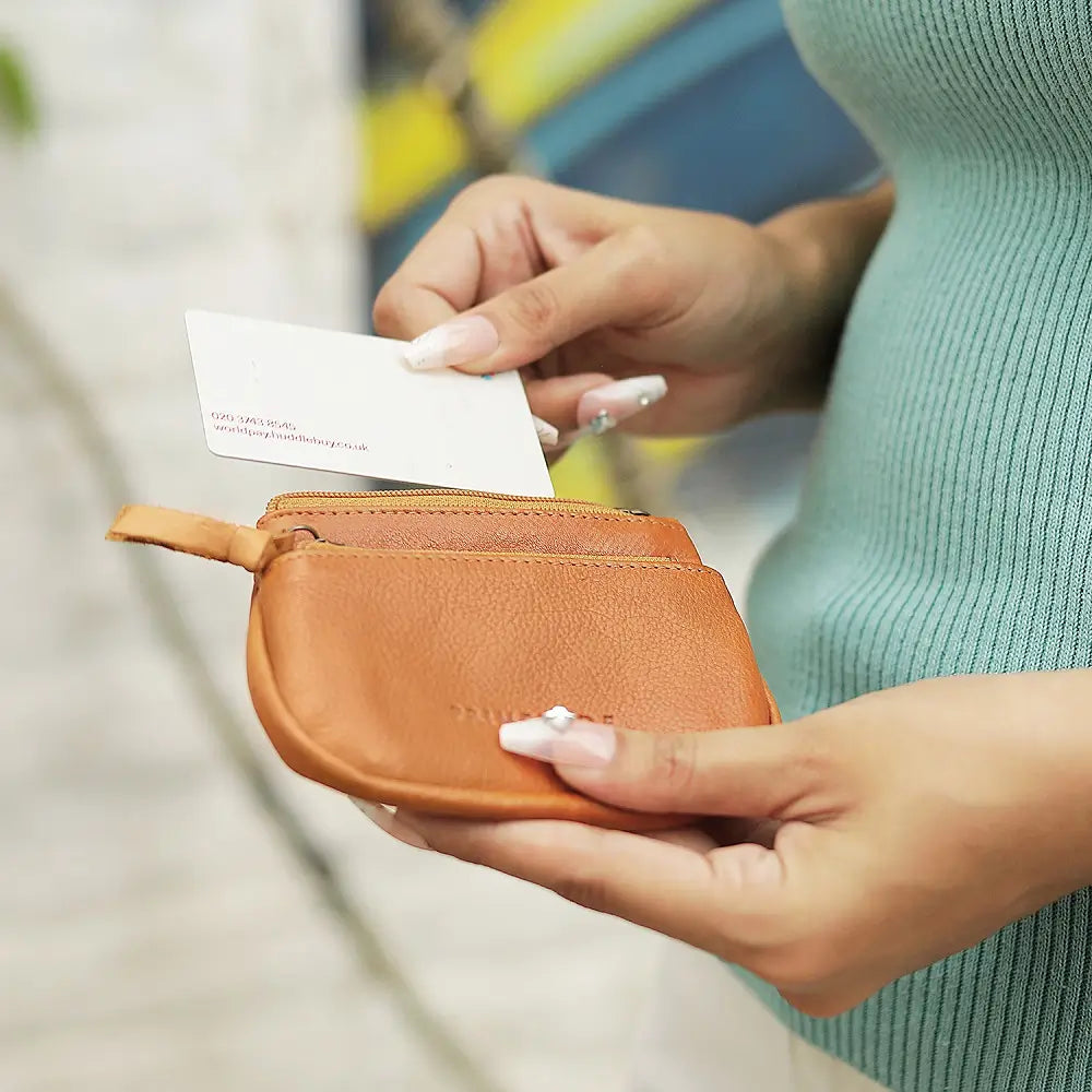 Person holding a Cognac leather wallet and a business card with a blurred background