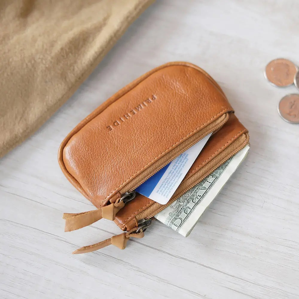 Cognac  leather wallet with money and coins on a light wooden surface