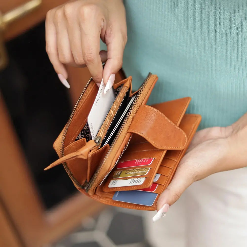 Cognac wallet with cards held open by a hand, blurred background