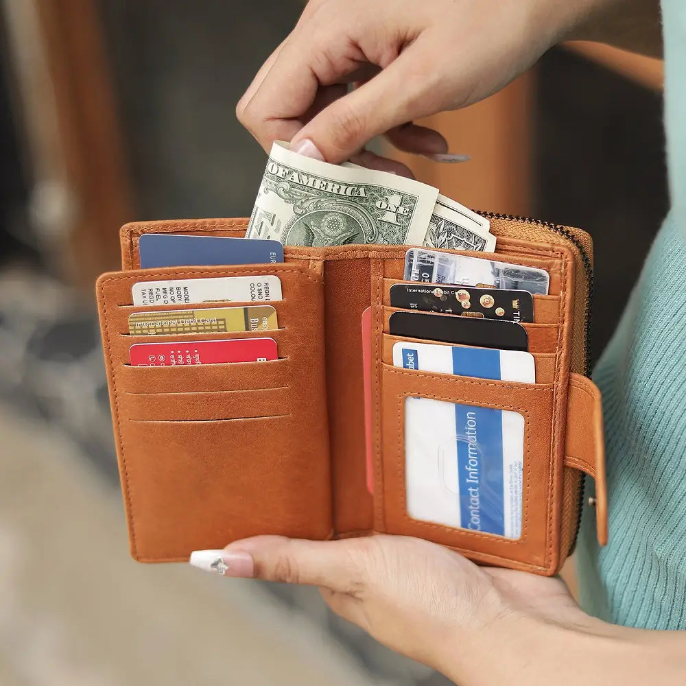 Cognac leather wallet with money and cards held by a person