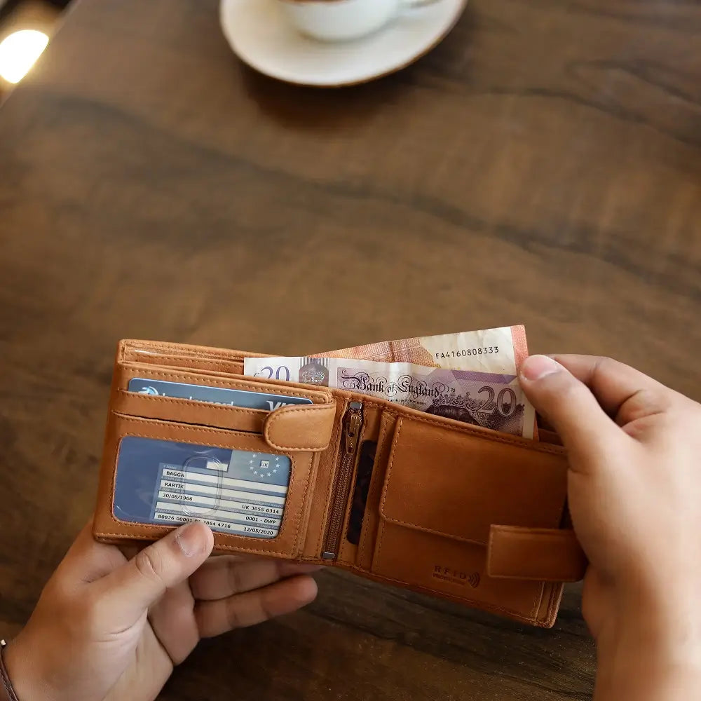 Person holding a cognac leather wallet with a blurred background